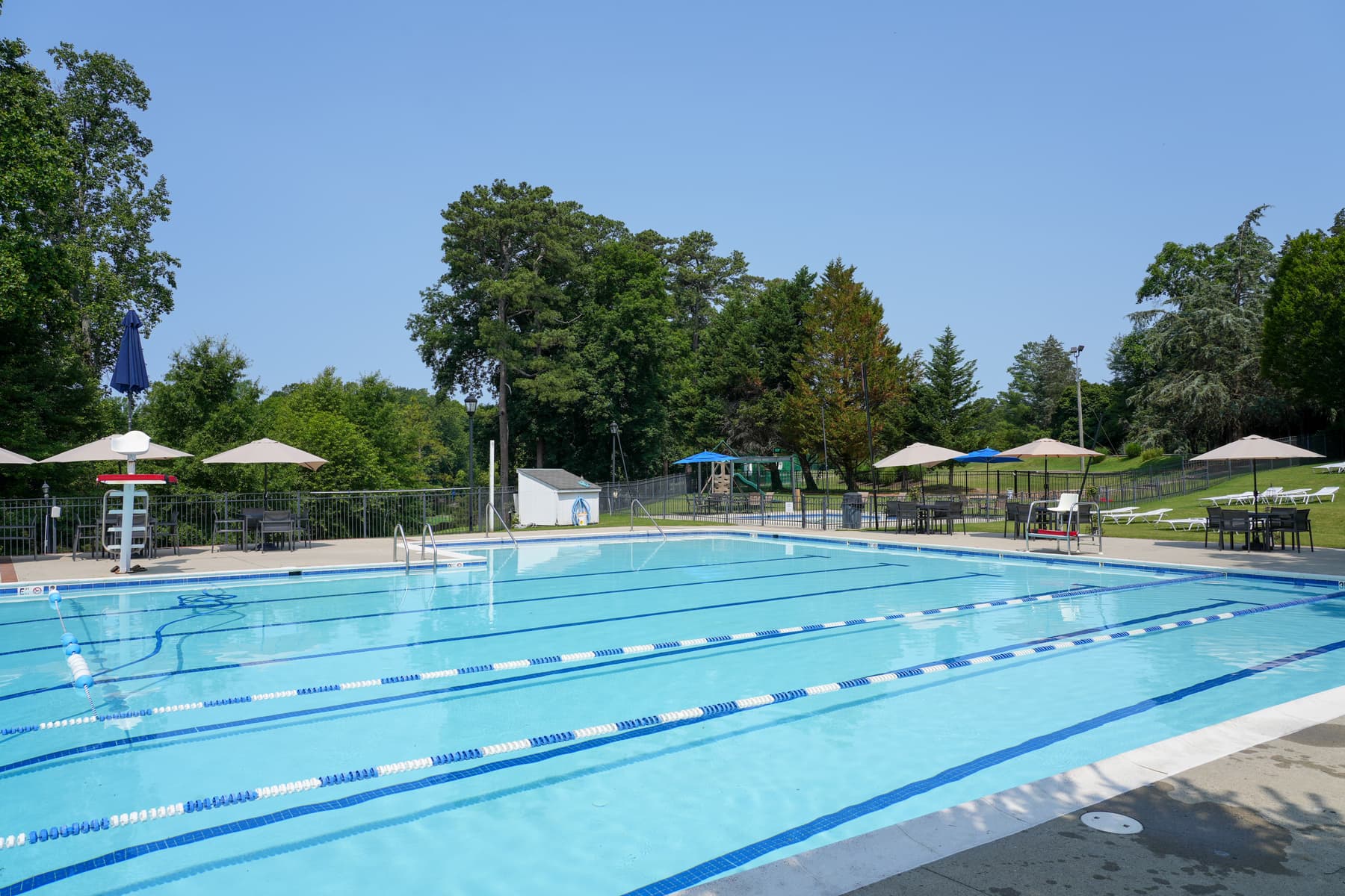 The lakeside pool with lane lines and shade umbrellas on a clear summer day